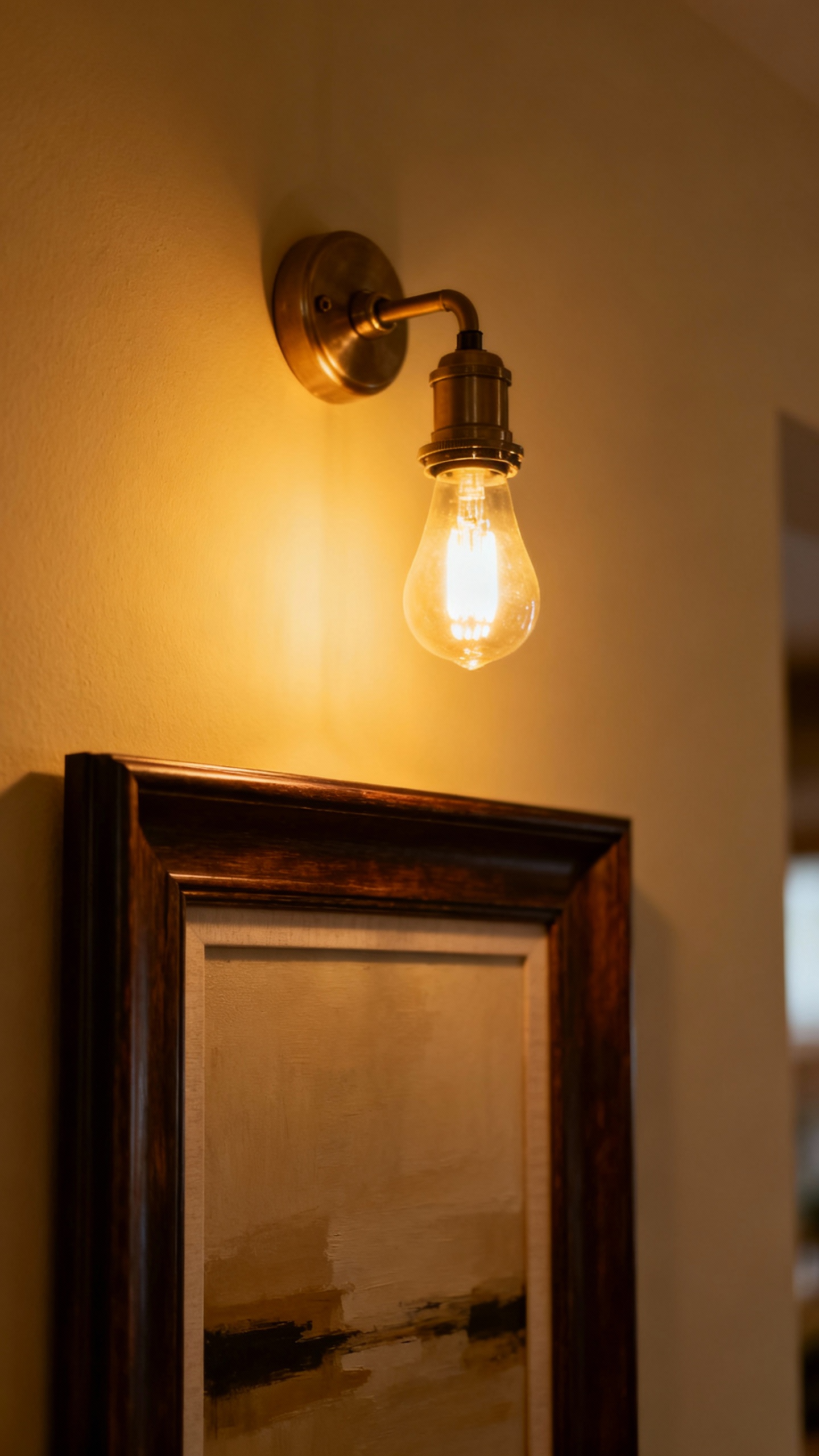 Cozy lighting scene: wall sconce with 2700K bulb, dim glow over framed art